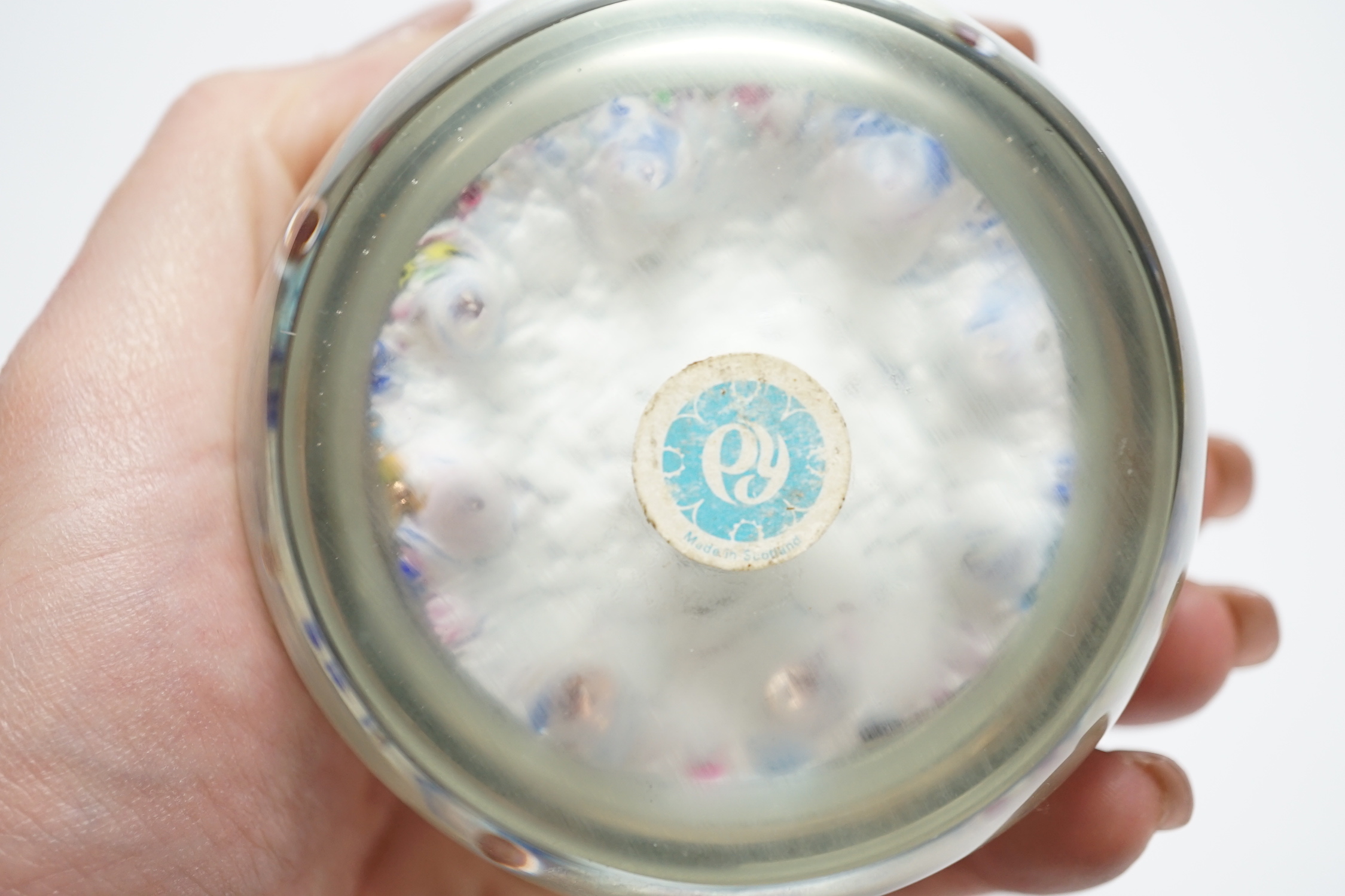 Two Paul Ysart glass paperweights, comprising a purple flower and latticino spoke on a blue jasper ground, ‘H’ cane, PY label, 7cm and ‘Harlequin’ glass paperweight, PY paper label, 8cm